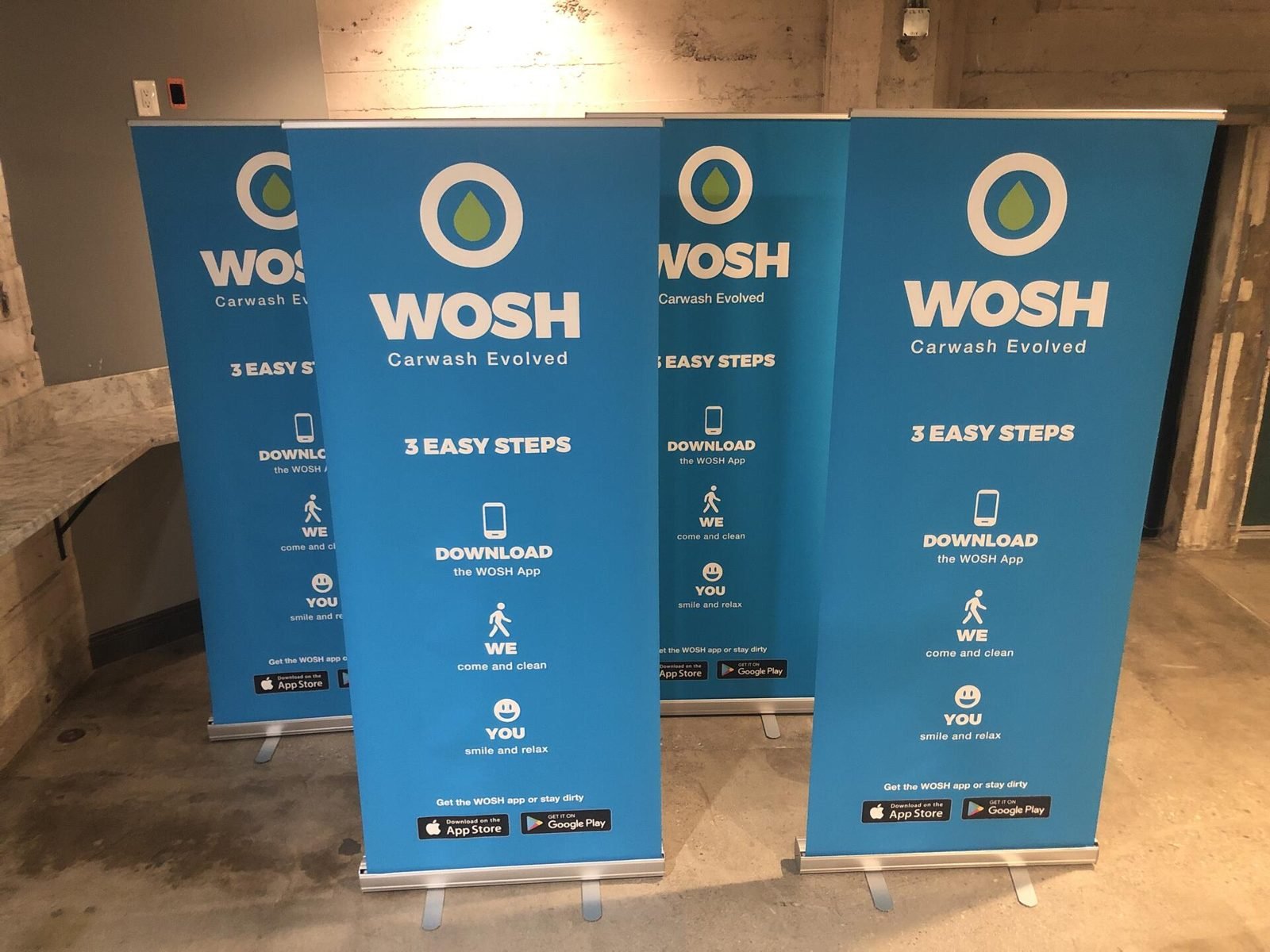 Four WOSH retractable banners in a warehouse space